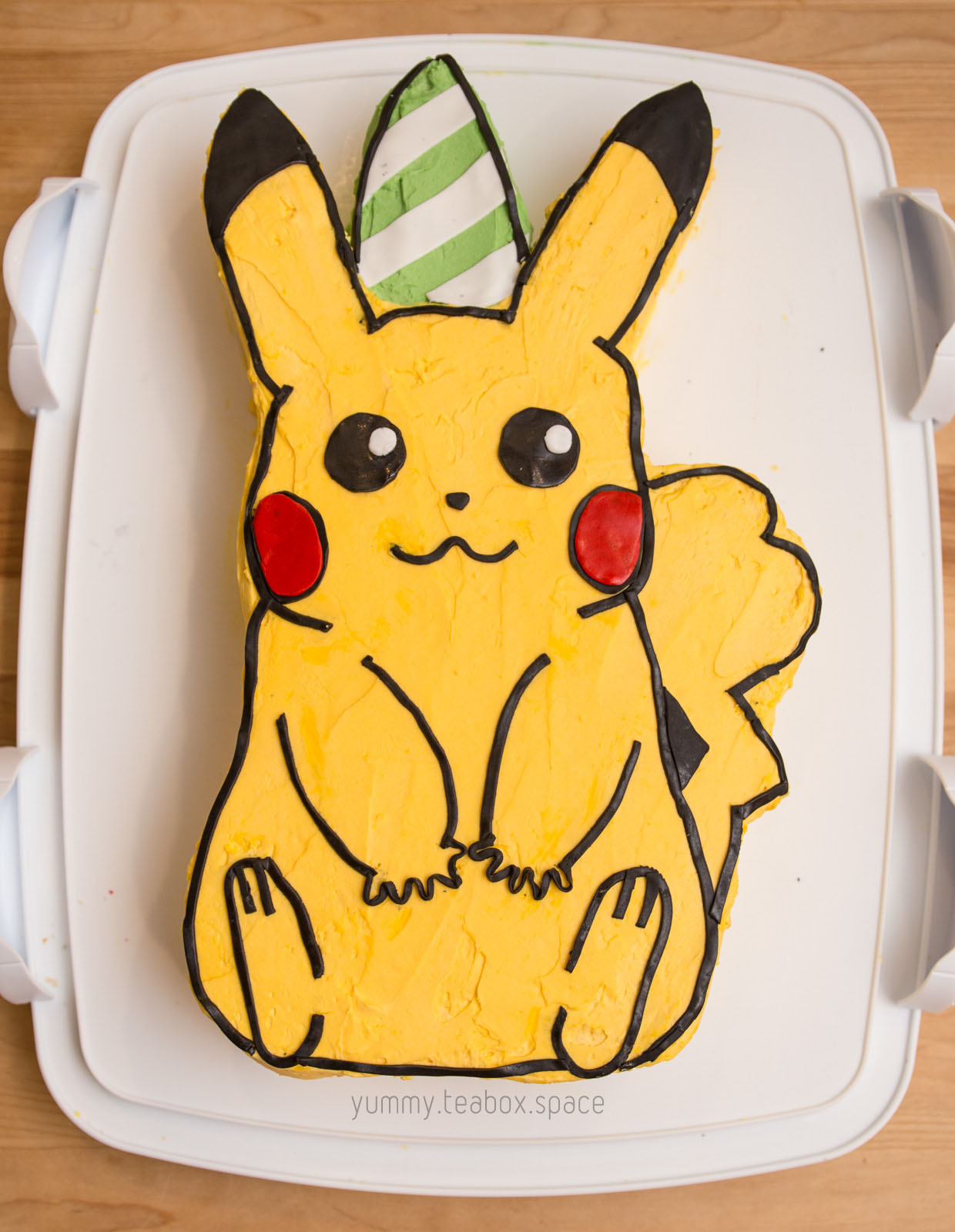 Cake that looks like a sitting Pikachu with a party hat.
