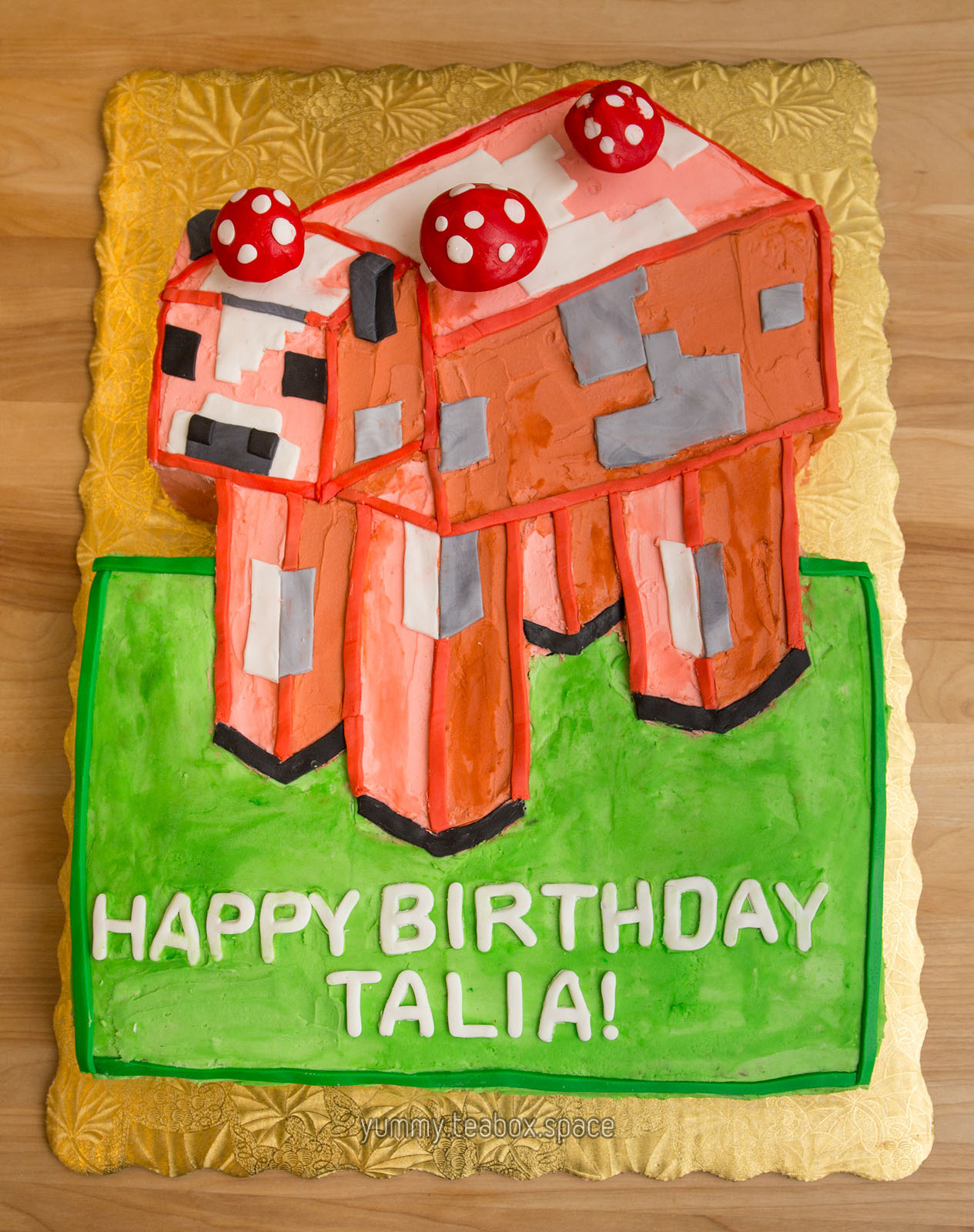 Cake that looks like a Minecraft Mooshroom, which is a red cow with mushrooms growing on top. Cake says "Happy Birthday Talia".