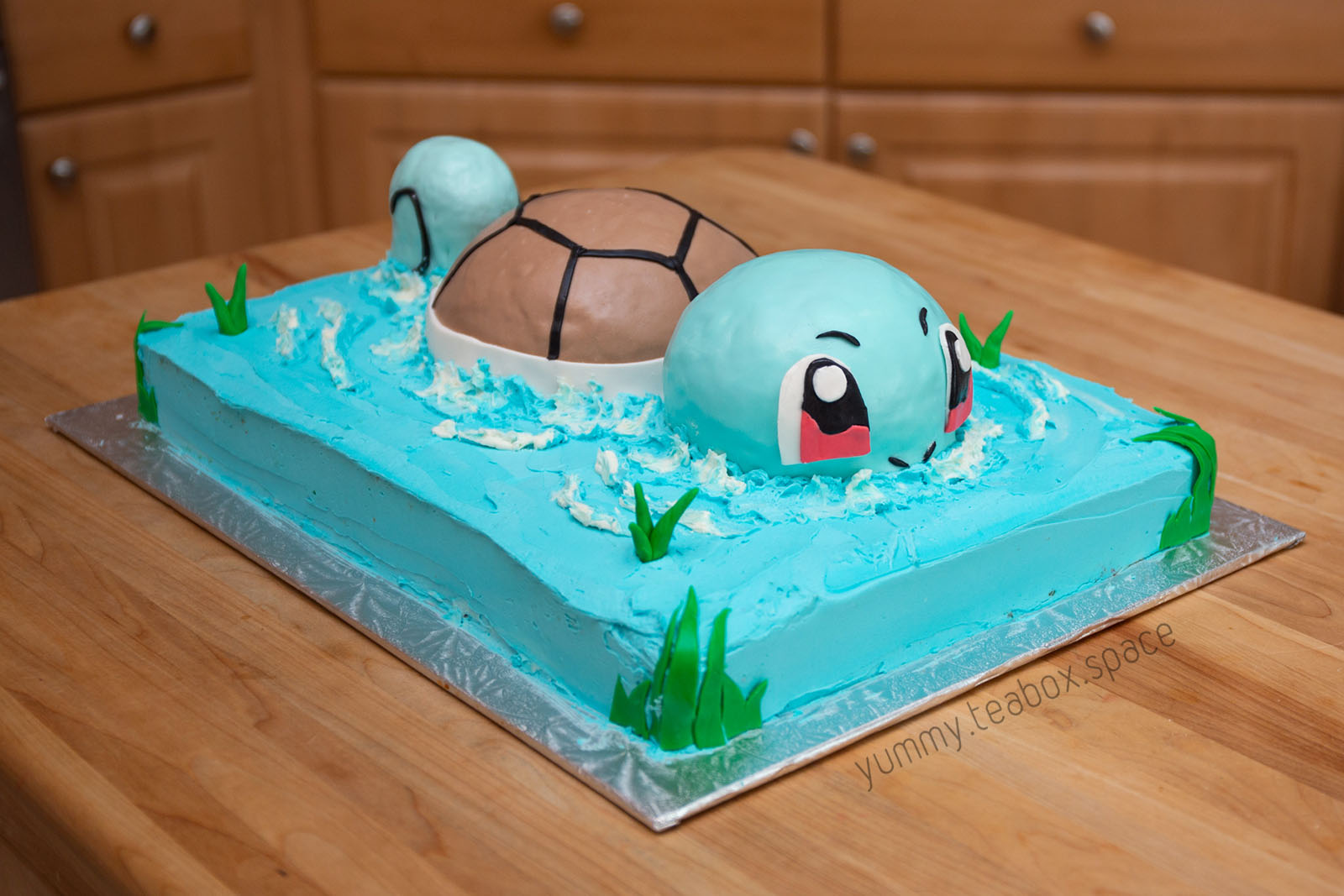 A blue cake that looks like water with Squirtle partially above the water swimming