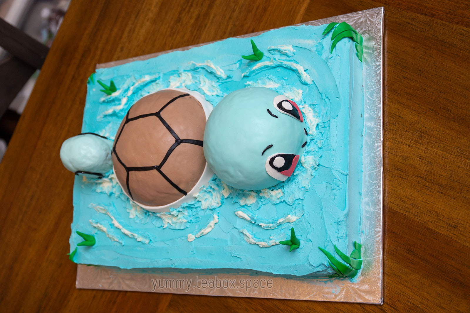 A blue cake that looks like water with Squirtle partially above the water swimming